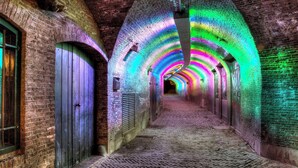 Un pasillo de ladrillo con techos abovedados e iluminación colorida.