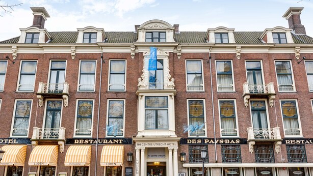 Un edificio histórico con varios establecimientos a nivel de calle, incluyendo un hotel, restaurantes y un bar.