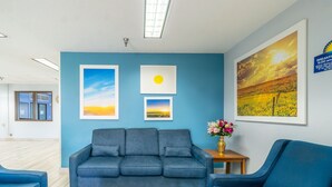 A room with a blue sofa, a wooden coffee table with magazines, and framed pictures on the wall.