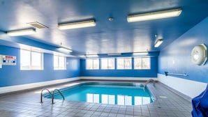 An indoor swimming pool with blue walls, tiled floor, and overhead lighting.