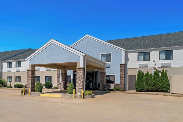 A hotel with a covered entrance, stone pillars, and a parking lot. - Best Western University Inn (Urbana)