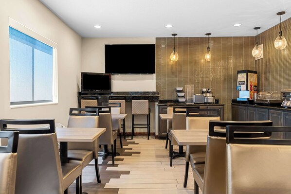 Un restaurante moderno con una televisión de pantalla plana, luces colgantes y una barra con una máquina de café.