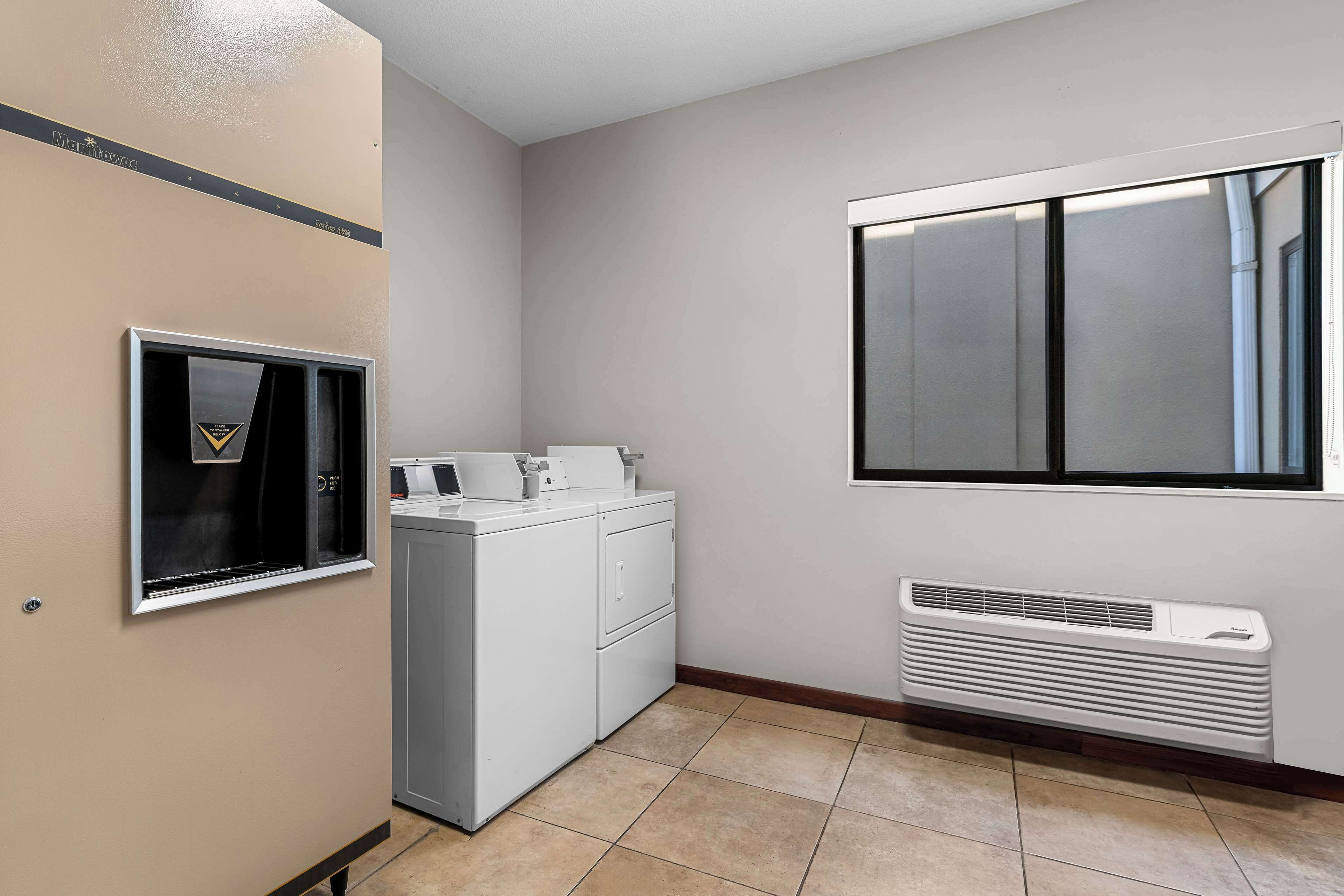 A laundry room with a washer and dryer, a vent, and a window.
