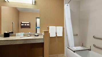Een moderne badkamer met een granieten wastafel, een spiegel, een handdoekrek en een douche met glazen deur.