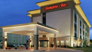 A Hampton Inn hotel with a covered entrance, multiple floors, and a well-lit facade.