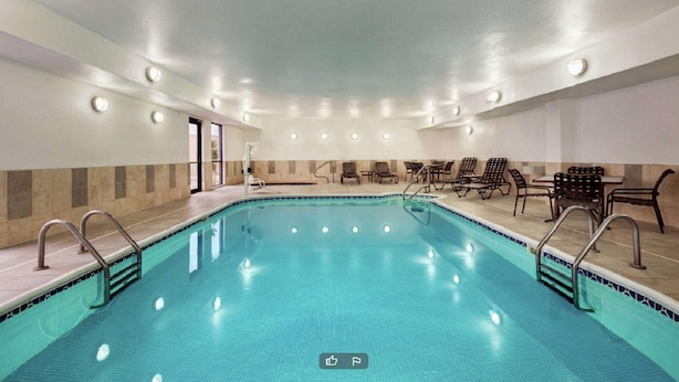 A large indoor swimming pool with multiple lanes, surrounded by lounge chairs and tables, and equipped with ceiling lights.
