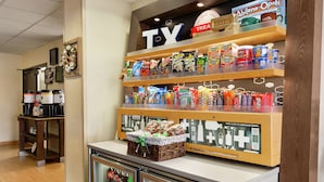 A snack display with various packaged foods and a beverage cooler.