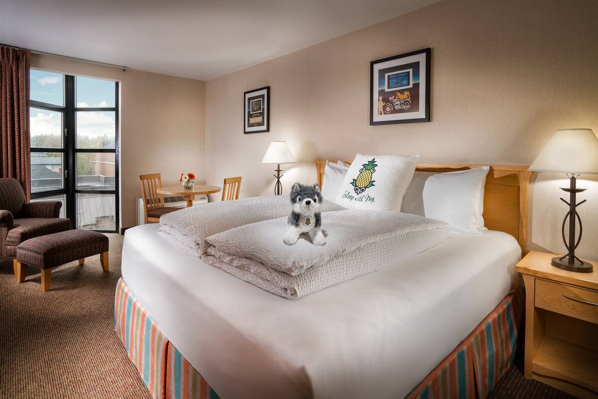 A hotel room with a large bed, a desk, a chair, and a window with curtains.