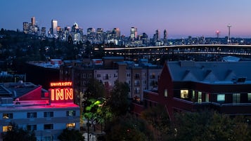 Une vue sur les gratte-ciel d’une ville, avec une enseigne bien visible de l’hôtel University Inn, un pont et la tour emblématique Space Needle de Seattle en arrière-plan.