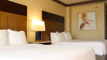 A hotel room with two beds, a nightstand with a lamp, and a wall-mounted artwork.