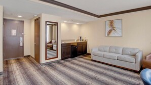 Una habitación de hotel con piso de madera, un sofá, una zona de cocina y una puerta.