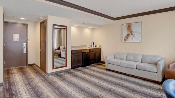Una habitación de hotel con piso de madera, un sofá, una zona de cocina y una puerta.