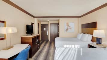A hotel room with a bed, desk, chair, television, and artwork on the wall.