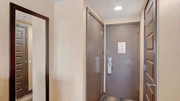 A hotel hallway with a carpeted floor, a wooden door frame, and a closed door with a lock and a keycard reader.