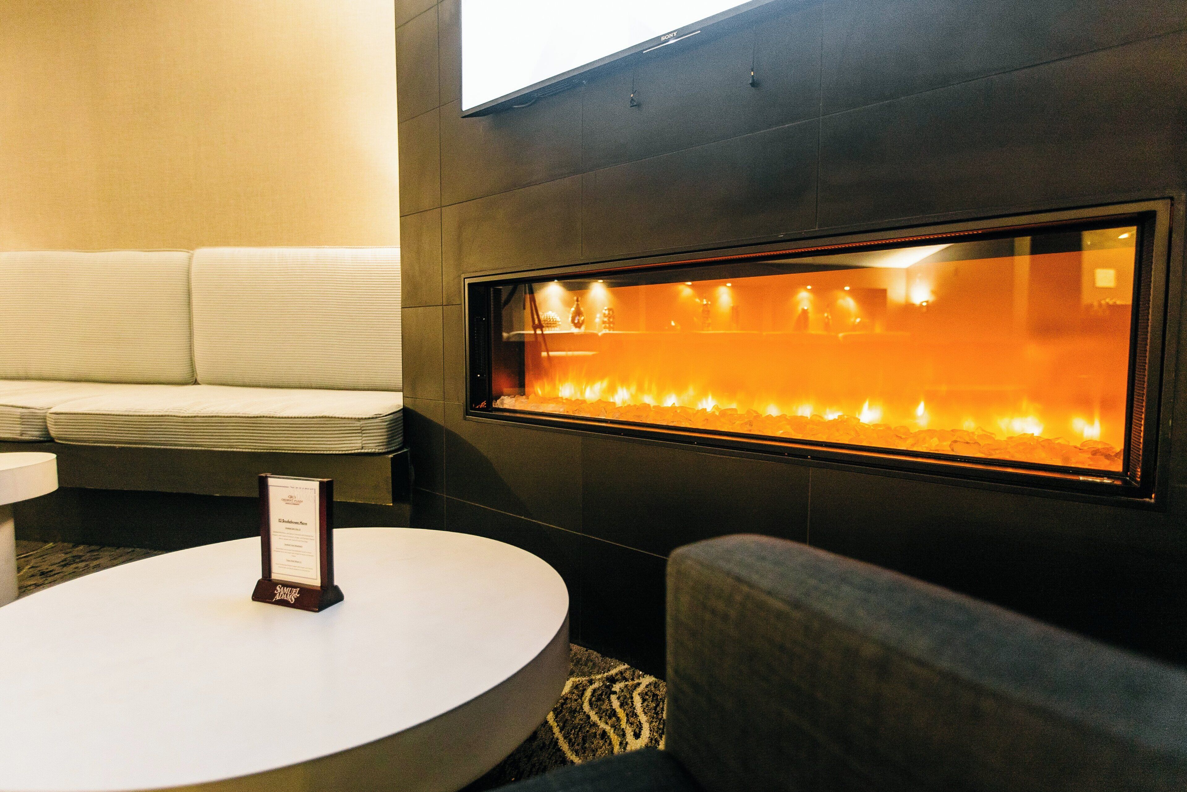 A modern interior with a sofa, a round table, and a wall-mounted fireplace.