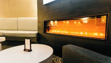 A modern interior with a sofa, a round table, and a wall-mounted fireplace.