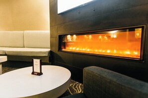 Ein modernes Interieur mit einer Couch, einem runden Tisch und einem an der Wand befestigten Kamin.