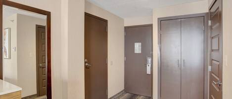 Un pasillo con tres puertas, un banco de madera y una lámpara en el techo.