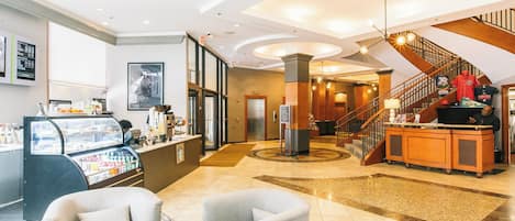 A hotel lobby with a reception desk, seating area, and a staircase.