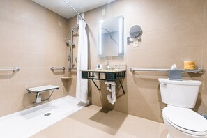 Un baño moderno con ducha a nivel de suelo, inodoro y lavamanos.