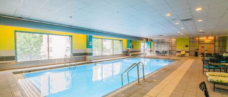 Une piscine à l’eau d’un bleu cristallin, entourée de murs jaunes et bleus, et dotée d’un sol carrelé.