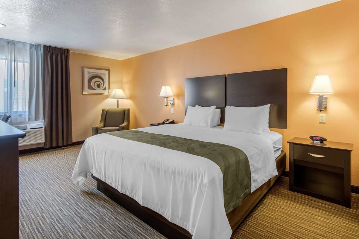 A hotel room with a large bed, two bedside tables, a desk, and a chair.