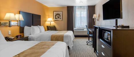 Ein Hotelzimmer mit zwei Betten, einem Fernseher, einem Schreibtisch und einem Sessel.