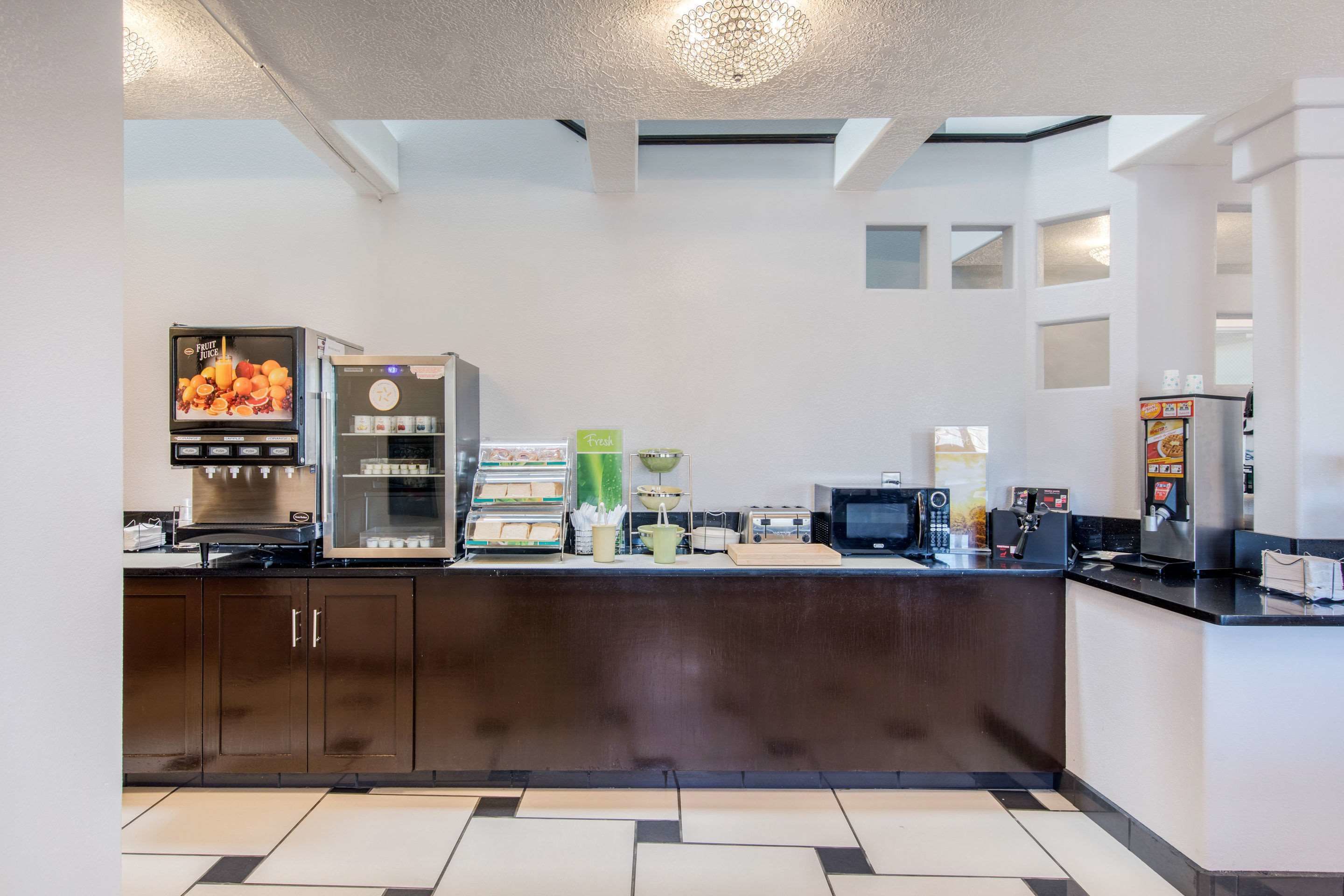 A modern kitchen with a coffee machine, a fruit juice dispenser, and a microwave.