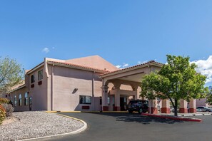 A hotel with a flat roof, arched entrance, and a covered parking area.