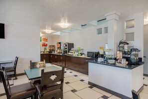 A modern kitchen with a central island, a dining area with a table and chairs, and a refrigerator.