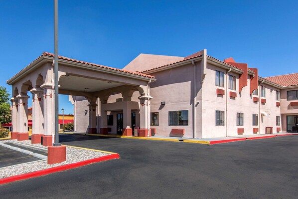 A hotel with a covered entrance, multiple windows, and a parking lot.