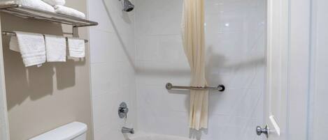 A bathroom with a bathtub, a toilet, a towel rack with towels, and a shower curtain.