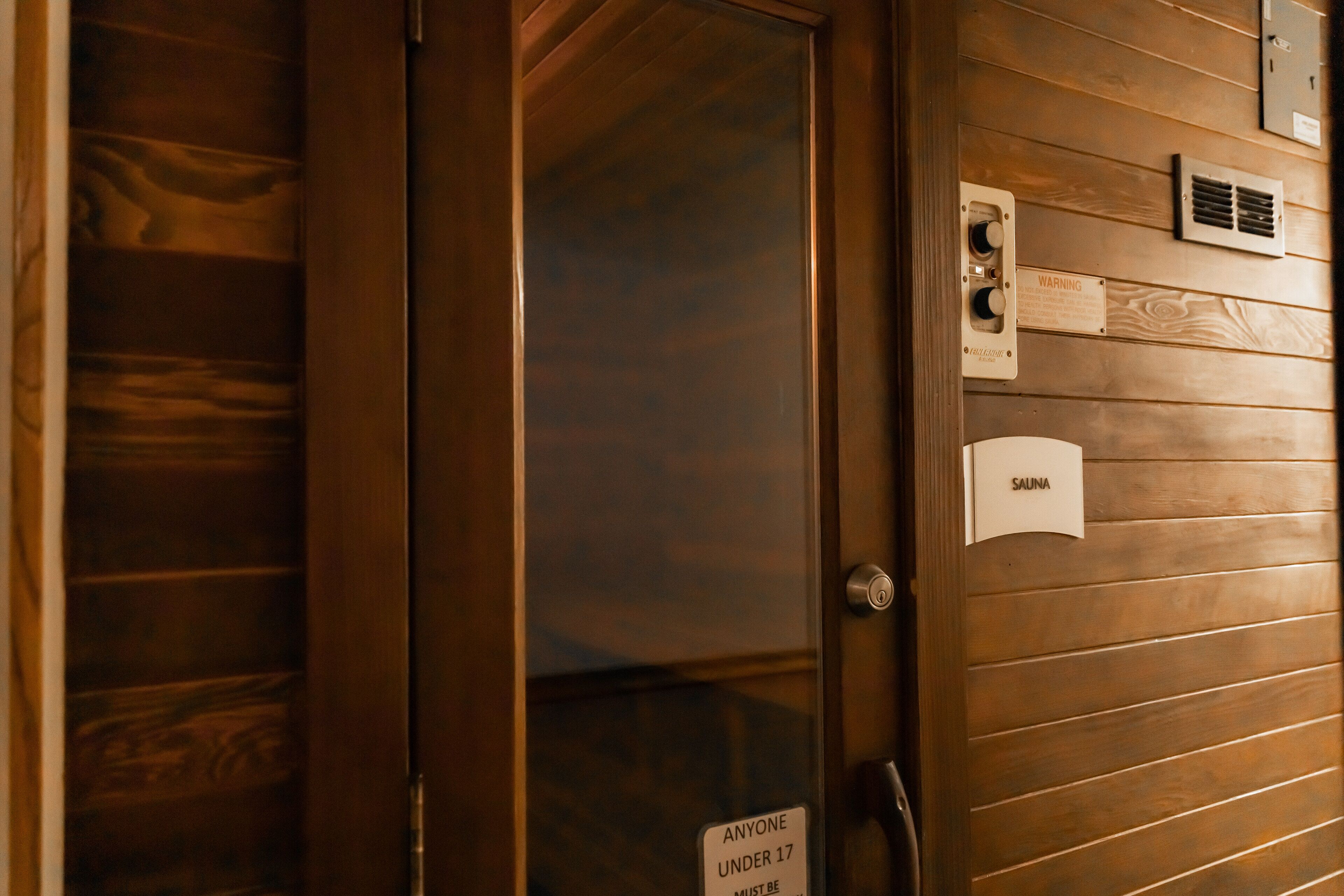 A wooden door with a sign stating "Anyone under 17 must be accompanied by an adult."