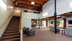 Uma sala de estar ampla com escada, lareira e espaço para refeições.