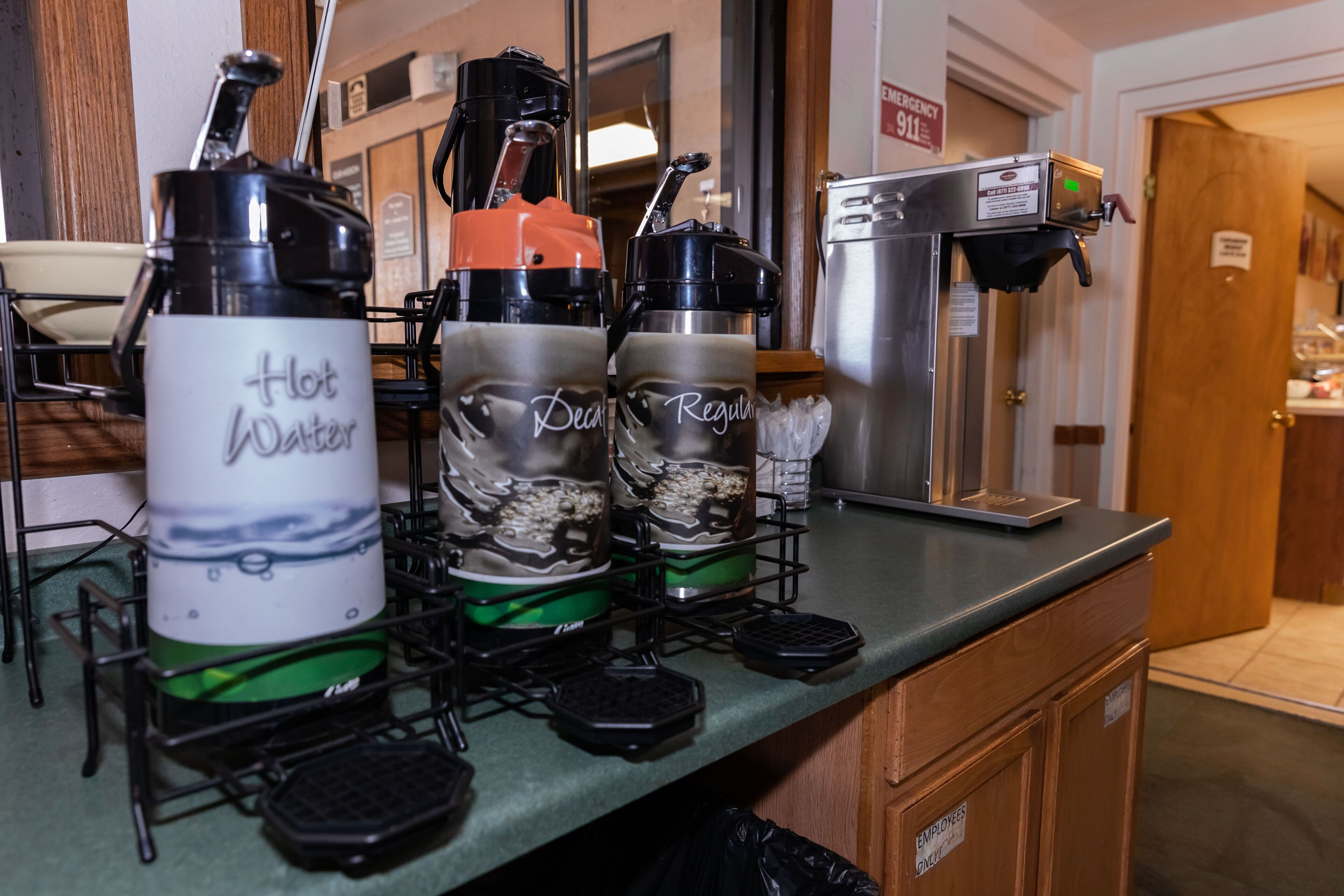 A kitchen area with coffee makers and a refrigerator.