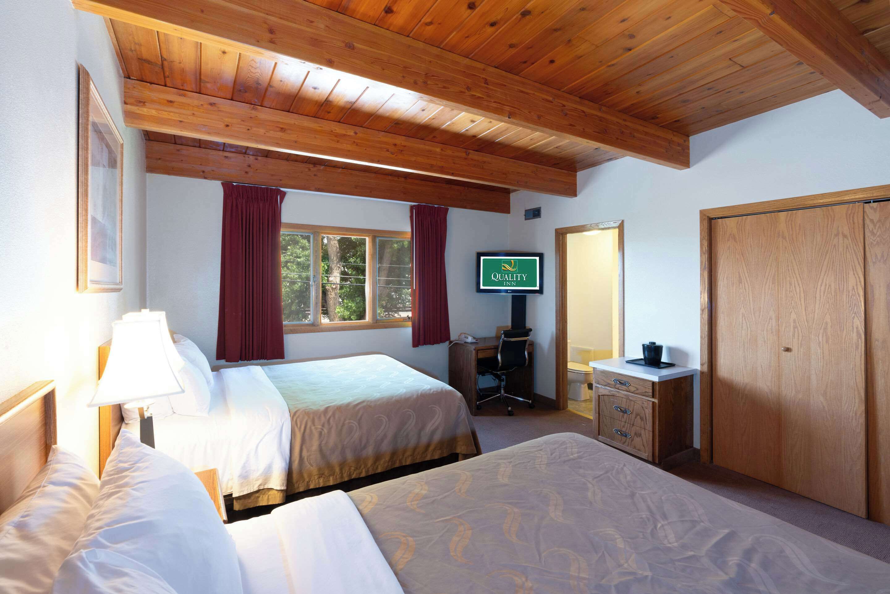 Habitación de hotel con dos camas, un escritorio, un televisor y un armario.