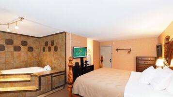A hotel room with a bathtub, a bed, a desk, and a television displaying the hotel name.