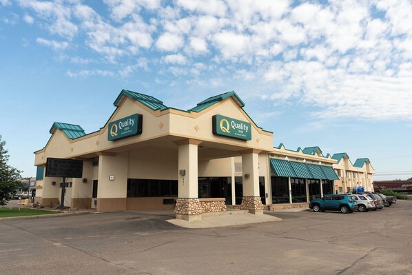 A Quality Inn hotel with a beige facade, green roof, and multiple entry points.