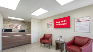 A Red Roof Inn reception area with a Red Roof sign, a Red Roof Rewards poster, and a Red Roof Pets poster. - Red Roof Inn Tucson South - Airport (Tucson)