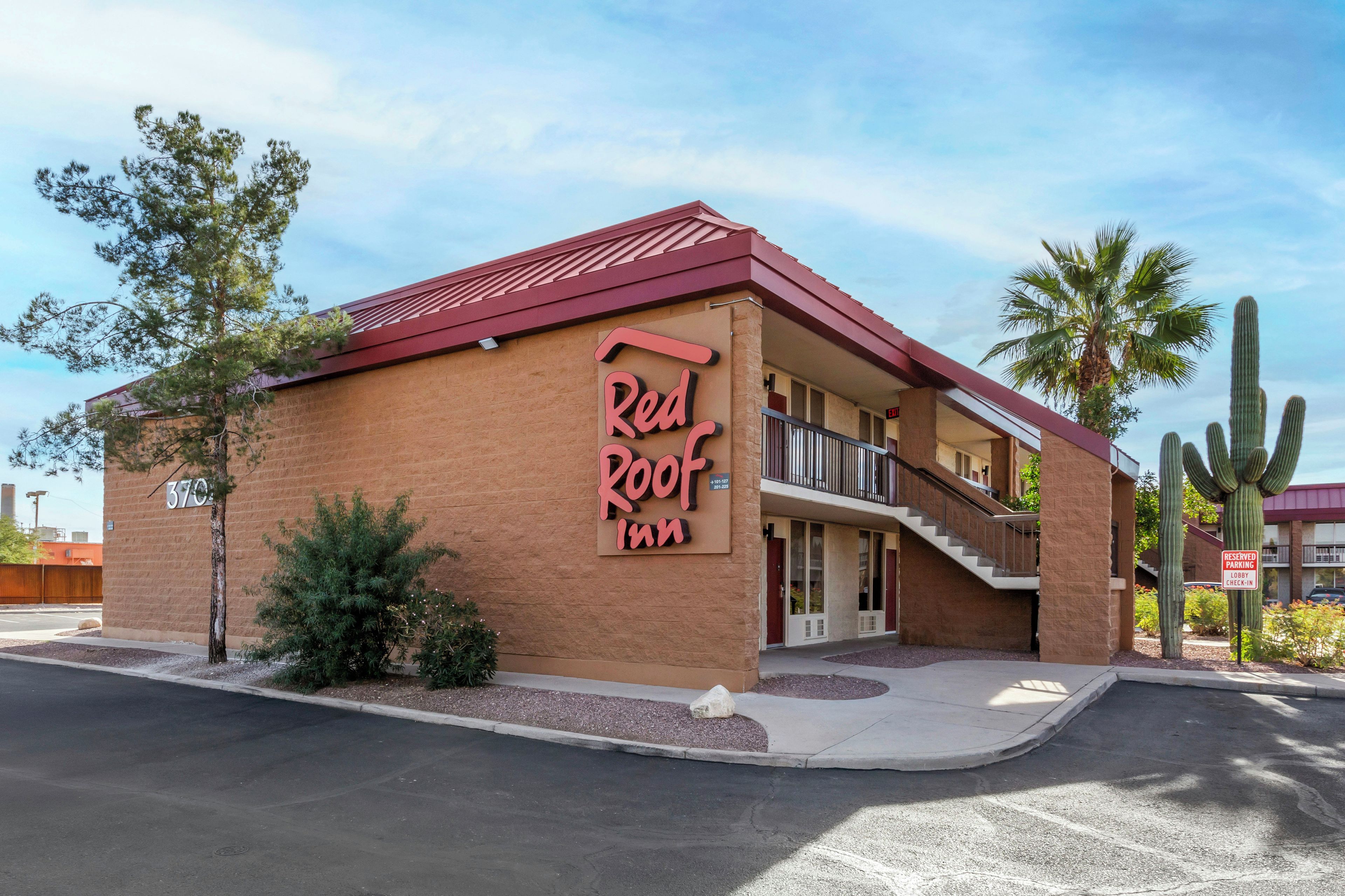 Un hotel Red Roof Inn con techo rojo, balcón y señalización que indica estacionamiento reservado.