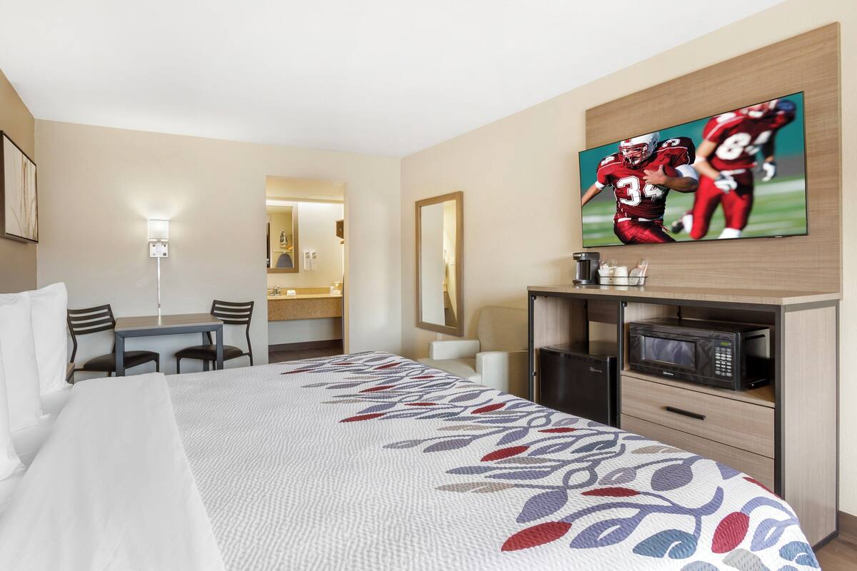 Une chambre d’hôtel équipée d’un lit, d’un bureau, d’une chaise, d’un four à micro-ondes et d’un téléviseur à écran plat fixé au mur.