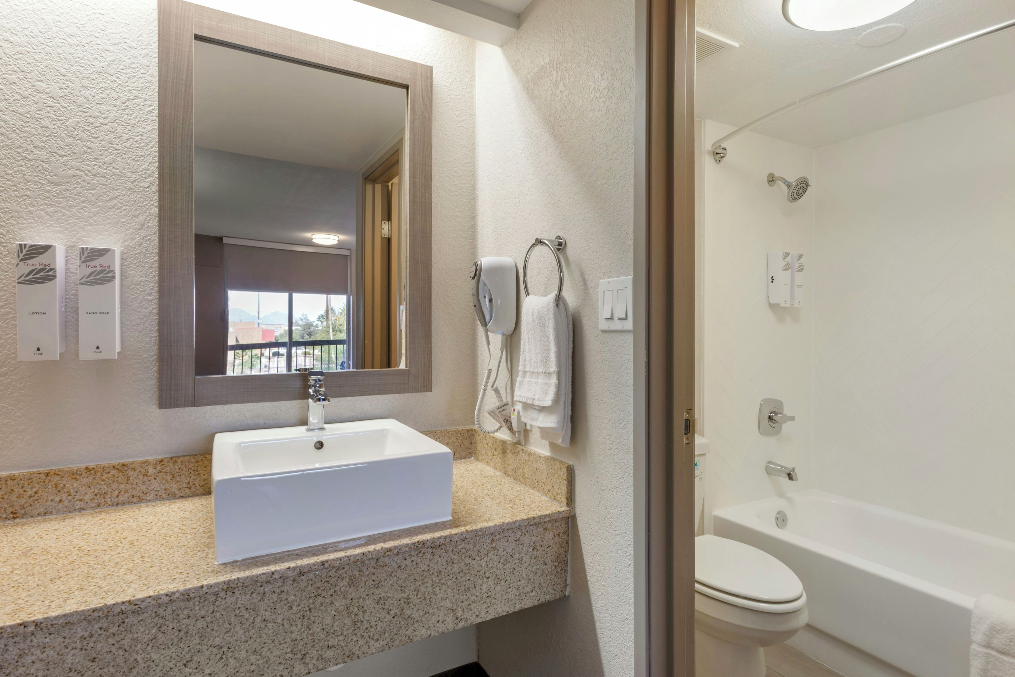 Een badkamer met een wastafel, spiegel, handdoekrek en douche.