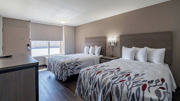 A hotel room with two beds, a desk, a window, and a nightstand with a lamp. - Red Roof Inn Tucson South - Airport (Tucson)