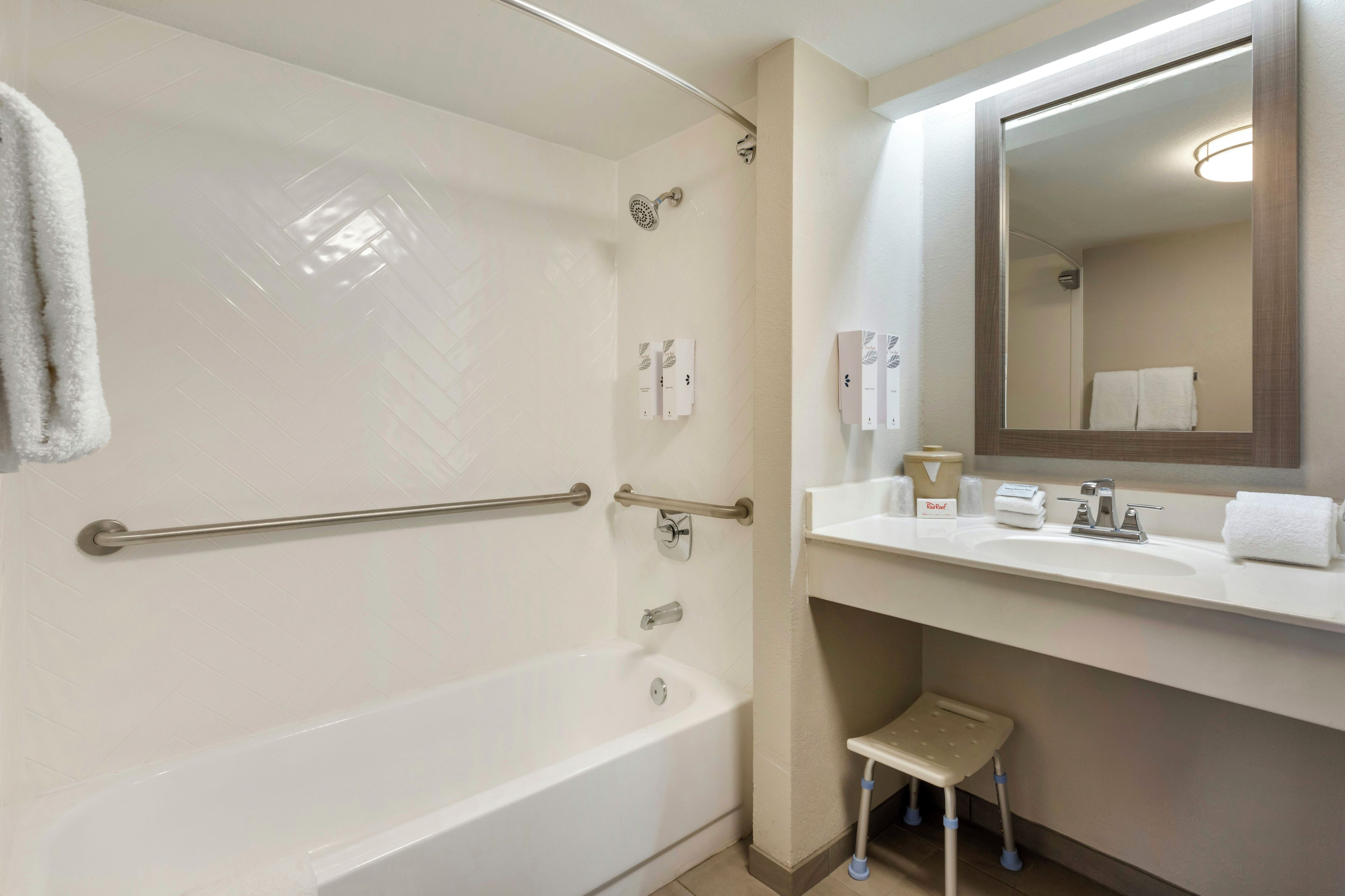 A bathroom with a bathtub, a shower, a sink, a mirror, and a step stool.