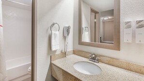 A bathroom with a sink, mirror, towel rings, and a hand dryer. - Red Roof Inn Tucson South - Airport (Tucson)