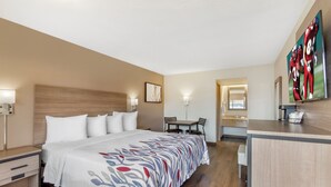 A hotel room with a large bed, bedside tables, a desk, and a chair. - Red Roof Inn Tucson South - Airport (Tucson)