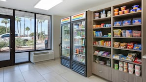 A convenience store with refrigerated beverage dispensers, snack shelves, and a view of palm trees outside. - Red Roof Inn Tucson South - Airport (Tucson)