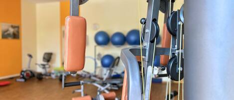 Une salle de sport équipée de matériel d’exercice, notamment une machine de musculation et des ballons d’exercice, que l’on aperçoit à l’arrière-plan.
