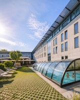 Un edificio moderno con piscina, sillas de descanso y un paseo cubierto.