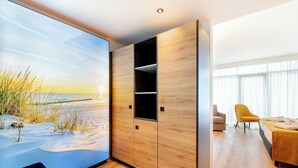 Une chambre moderne dotée d’une grande fenêtre, d’un plancher en bois, d’un lit, d’une chaise et de rangements intégrés.